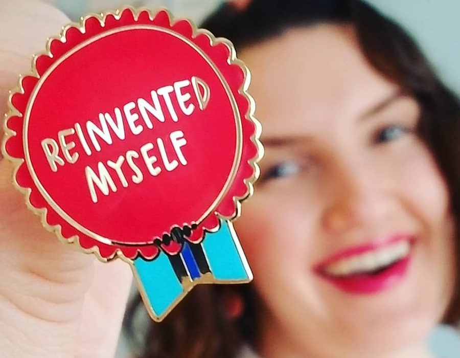 Rachel holding pin that says "Reinvented Myself"