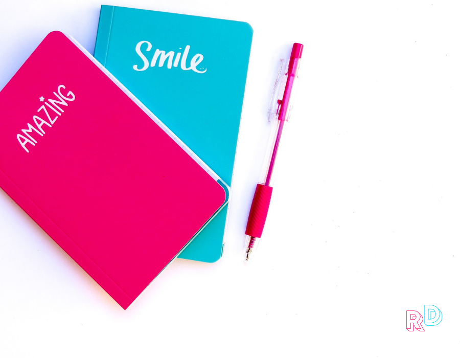 Pink and blue notebook with a pink pen on a white background